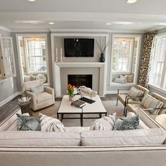 a living room filled with furniture and a flat screen tv mounted on the wall above a fireplace