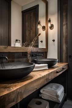 A rustic bathroom with a wooden vanity, black vessel sinks, wall-mounted faucets, a mirror with wooden frame, and industrial-style light fixtures. Dark Farmhouse Bathroom, Industrial Bathroom Ideas, Small Bathroom Makeovers, Modern Rustic Bathroom, Rustic Modern Bathroom, Design For Small Spaces, Barn Bathroom, Farmhouse Bathroom Ideas, Dark Bathrooms