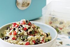 a white bowl filled with rice and vegetables next to a blue box on a table