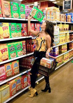 a woman is shopping in a grocery store with her back to the camera as she looks at cereal