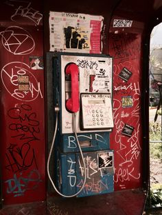 an old fashioned pay phone is covered in graffiti