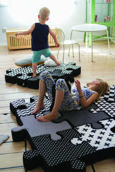 two children are playing on an inflatable piece of art that looks like puzzle pieces