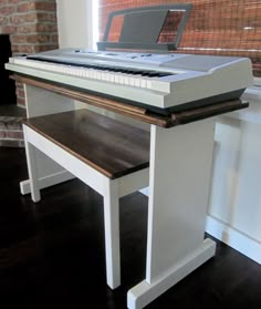 a desk with a laptop on top of it in front of a brick wall and window