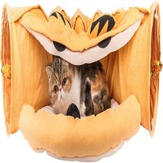 a cat is sitting in an animal bed with a tiger pattern on it's face