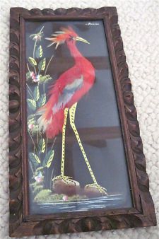 a painting of a red bird on display in a frame