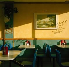 the interior of a restaurant with blue chairs and tables in front of yellow painted walls