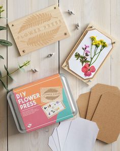 some crafting supplies are laying out on a wooden table next to flowers and cards