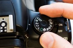 a person holding a camera with their thumb on it's button and the other hand