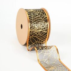 a roll of black and gold foiled spider web ribbon on white background with one spool cut out