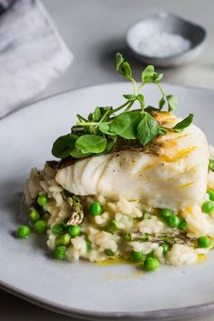 a white plate topped with fish and peas