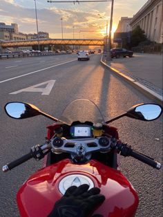 a red motorcycle is parked on the side of the road as the sun sets behind it