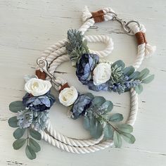 a white rope with flowers and leaves attached to it on top of a wooden table