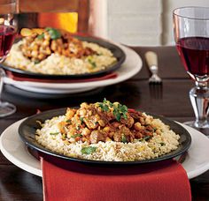 two plates filled with food on top of a table next to glasses of red wine