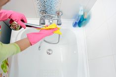 a woman in pink gloves is cleaning a sink