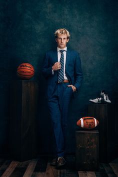 a man in a suit and tie standing next to basketballs