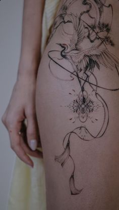 a woman's thigh with a bird and flower tattoo design on the side of her leg