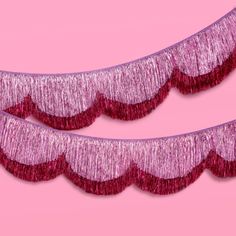 two pink tinsel fringes are on a pink background, one is red and the other is purple