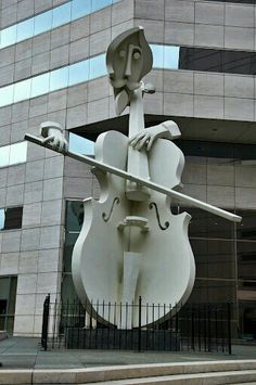 a statue of a man holding a violin in front of a building