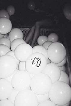 a bunch of balls that are sitting in a basket on the floor and one has an xo written on it