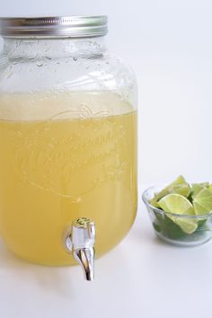 a mason jar filled with lemonade next to a bowl of limes