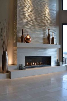 a modern fireplace with candles and vases on the mantle