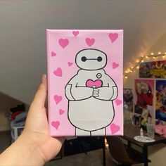 a hand holding up a small pink box with a cartoon character on it