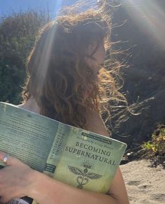 a woman reading a book on the beach