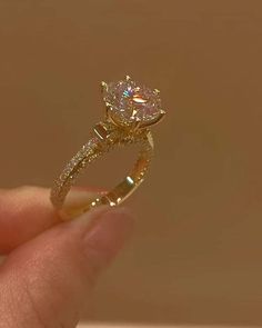 a hand holding a diamond ring in it's left hand, with the center stone on