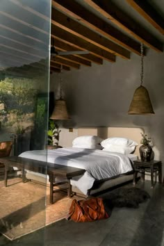 a bedroom with a large bed and two lamps hanging from the ceiling over it's headboard