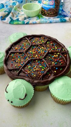 cupcakes with chocolate frosting and sprinkles on them are arranged in the shape of a turtle