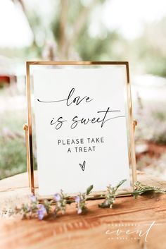 a sign that says love is sweet and please take a treat on top of a wooden table