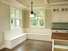 an empty kitchen with wood floors and white cabinets, along with a breakfast nook