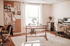 a room with a desk, chair and computer on the table in front of a window