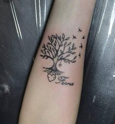 a small tree tattoo on the arm with birds flying around it and hearts in the air