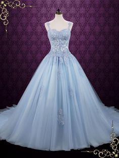 a light blue ball gown is on display in front of a purple wall with ornate ornaments