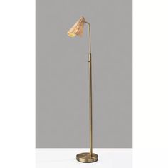 a floor lamp with a beige shade on the top and a gold base, sitting on a white surface