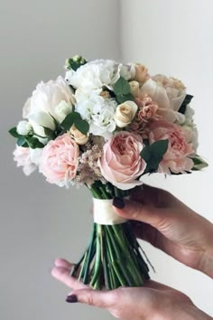 a person holding a bouquet of flowers in their hand with white and pink blooms on it