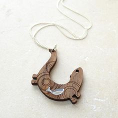 This gorgeous little pendant featuring an otter and his fish will make an original and eye-catching addition to your necklace collection! The tiny inlaid silver mirror fish gives a fantastic sparkle and the otter's sleek body has been engraved with a delicate pattern of ripples to create the impression of swimming through water.The otter is made from walnut wood veneer and hangs from a fine silver-plated chain.The otter sits on its own individual presentation card and comes prettily wrapped then Presentation Cards, Fish Pendant, Necklace Collection, Silver Mirror, Silver Mirrors, Otters, Wood Veneer, Walnut Wood, Fine Silver