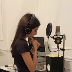 a woman with headphones on sitting in front of a microphone