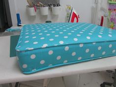 a blue and white polka dot covered case sitting on top of a sewing machine table