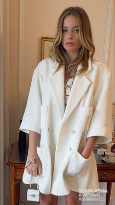 a woman standing in front of a mirror wearing a white coat