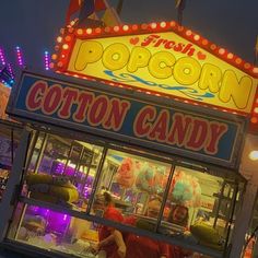 a cotton candy stand in front of a carnival at night