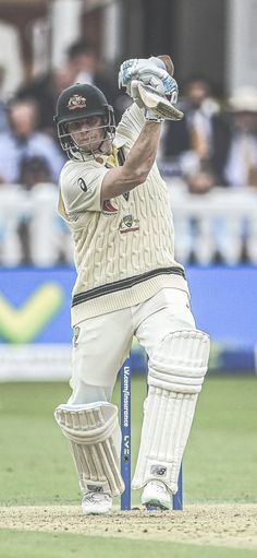 a man holding a cricket bat on top of a field