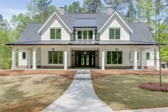 a large white house with lots of windows on the front and side of it, surrounded by trees