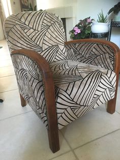 a chair that is sitting on the floor in front of a potted plant with flowers