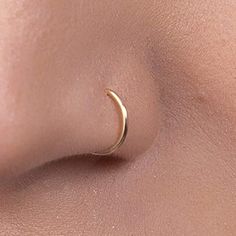 a woman's nose with a small gold crescent ring on top of her nose