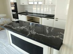 a kitchen with white cabinets and black marble counter tops, along with an island in the middle