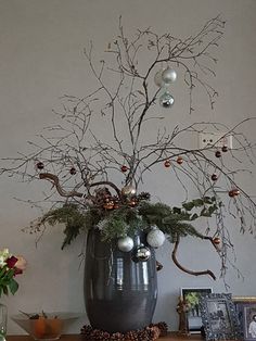 a vase filled with branches and ornaments on top of a table