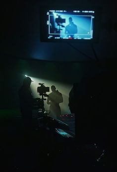 the silhouettes of two people in front of a television screen at night with lights on