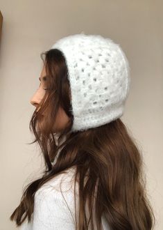 a woman with long hair wearing a white crochet beanie hat on her head